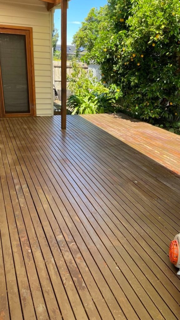 Wooden deck extending from a house with a door, sunny weather, and a lemon tree heavy with fruit in the yard nearby.